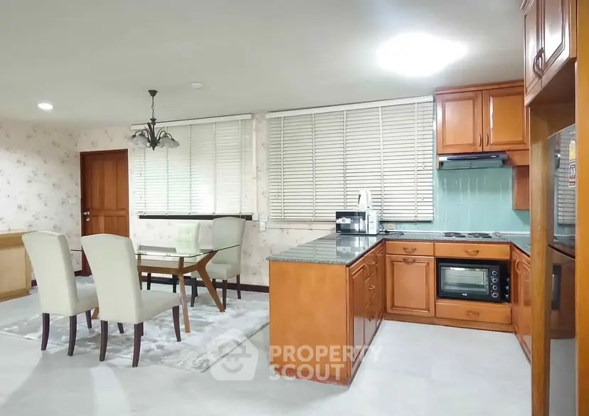 Spacious kitchen with dining area, featuring wooden cabinets and modern appliances.