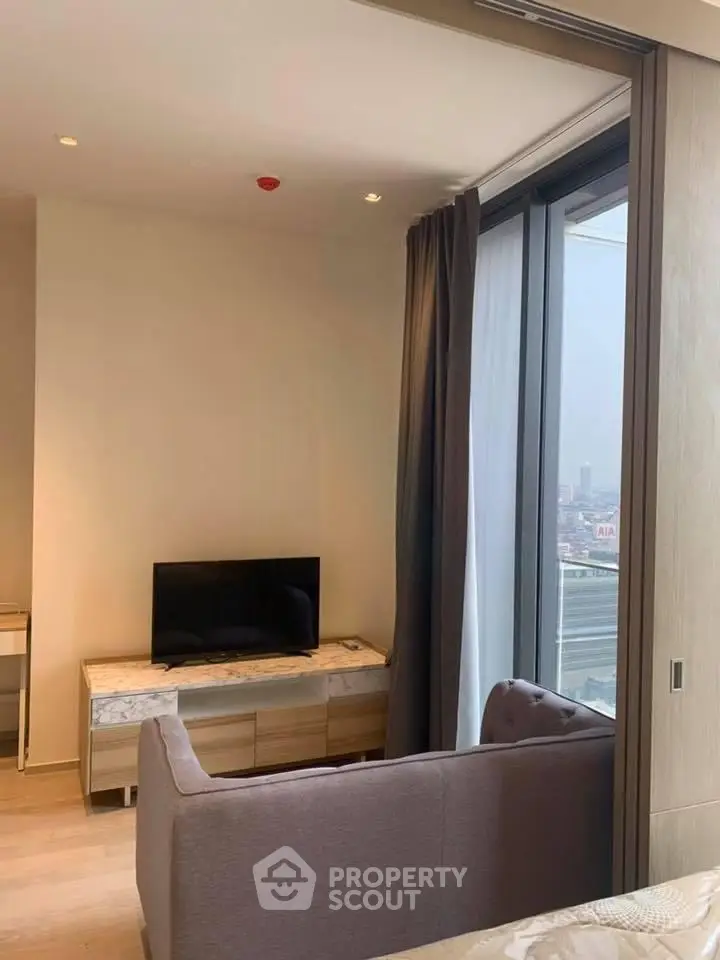 Modern living room with large window and city view, featuring a sleek TV stand and cozy sofa.