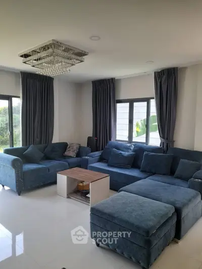 Spacious living room with elegant blue sofas and modern chandelier