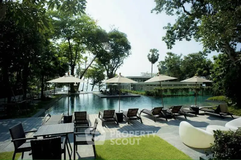 Luxurious outdoor pool area with sun loungers and lush greenery, perfect for relaxation.