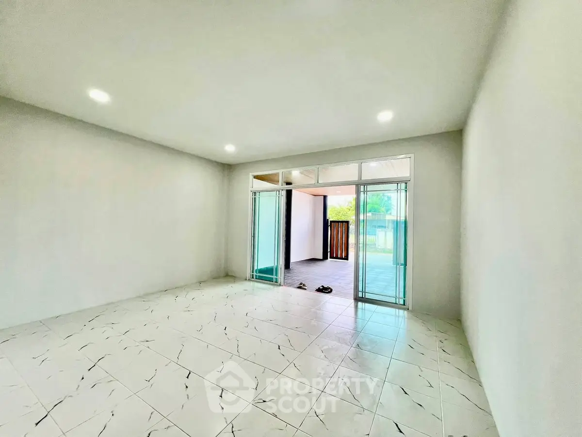 Spacious modern living room with large sliding glass doors and tiled flooring