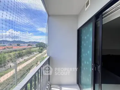 Bright balcony with safety netting and scenic view of greenery and cityscape.