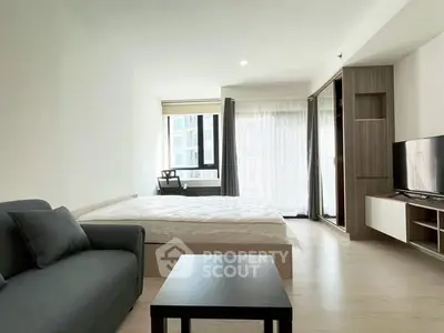 Modern studio apartment with cozy living area and large windows for natural light.
