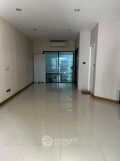 Spacious empty room with large windows and glossy tiled floor