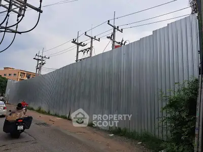 Construction site with metal fencing and power lines in urban area.