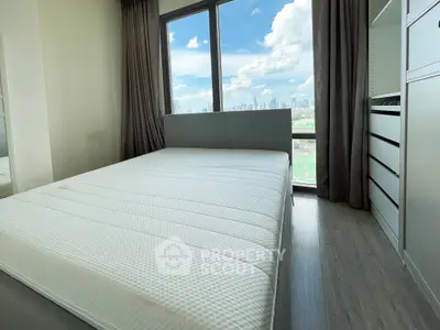 Modern bedroom with large window offering stunning city skyline view, featuring sleek built-in storage.