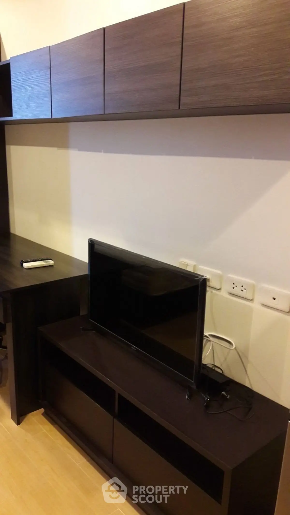 Modern living room with sleek dark wood furniture and flat-screen TV, perfect for contemporary urban living.