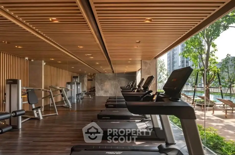 Modern gym with state-of-the-art equipment and scenic outdoor view in luxury residential complex.