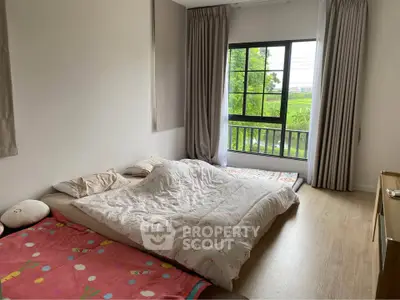 Cozy bedroom with large window and scenic view, featuring a comfortable bed and wooden flooring.