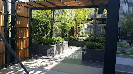 Modern garden area with pergola and lush greenery in urban residential complex.