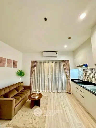 Modern living room with sleek kitchen, featuring cozy sofa and stylish decor, perfect for urban living.