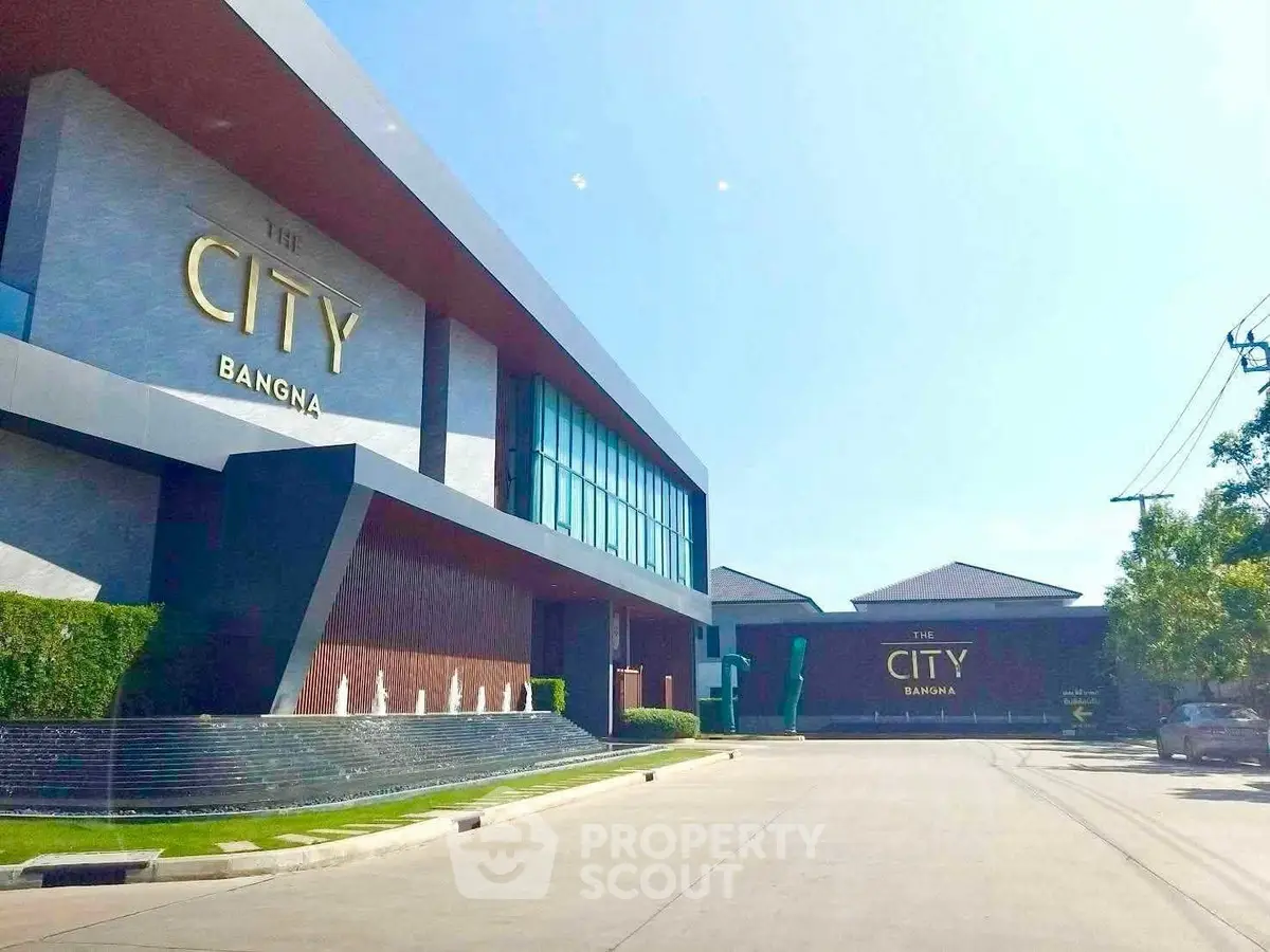 Modern residential complex entrance with sleek architecture and clear blue sky.