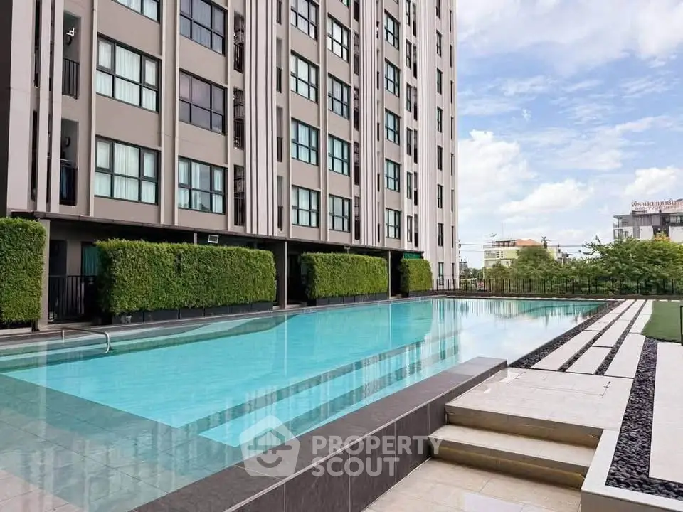 Modern apartment building with a luxurious outdoor pool and lush greenery.
