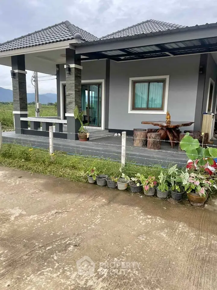 Charming modern house with a spacious porch and lush garden, perfect for serene living.