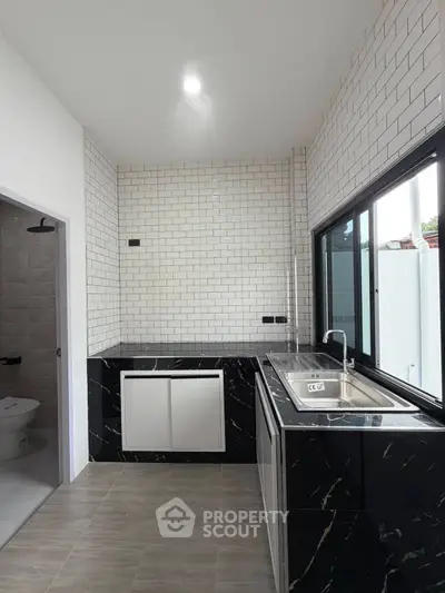 Modern kitchen with sleek black marble countertops and large window for natural light.