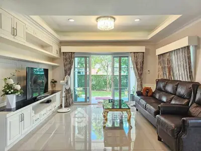 Spacious living room with elegant decor and garden view, featuring leather sofa and modern entertainment center.