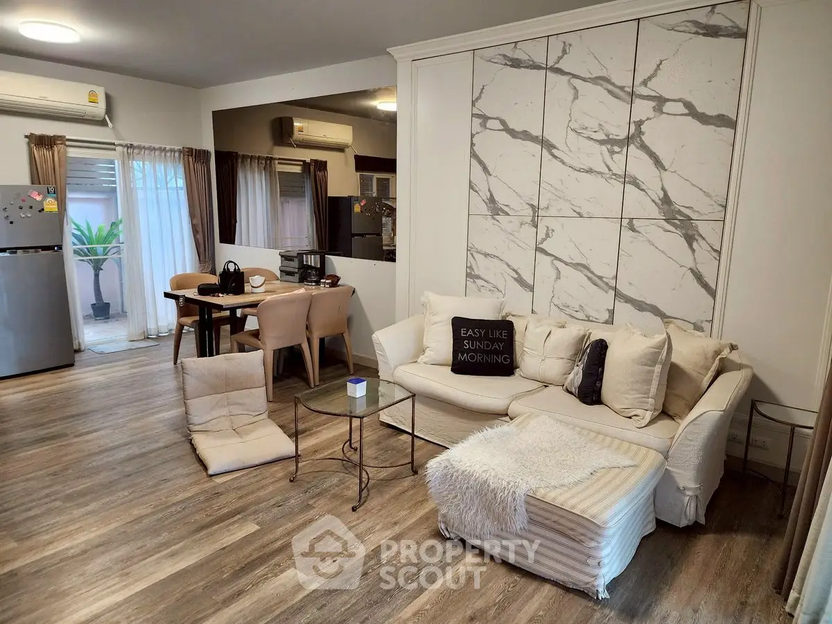 Spacious living room with modern decor and open dining area, featuring stylish furniture and natural light.