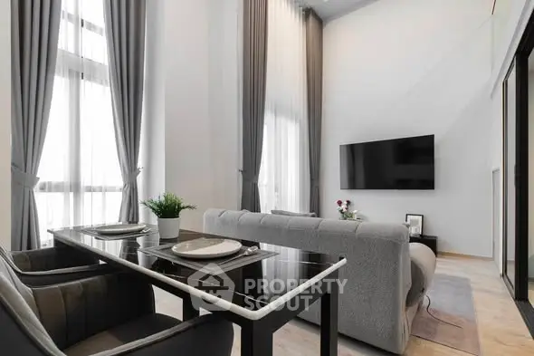 Modern living room with high ceilings, elegant curtains, and sleek furniture in a luxury apartment.
