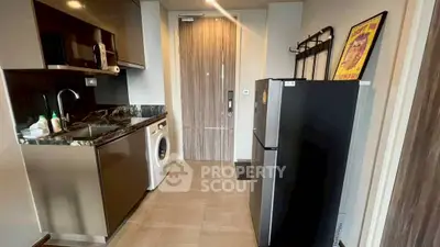 Modern kitchen with sleek appliances and washing machine in compact layout.