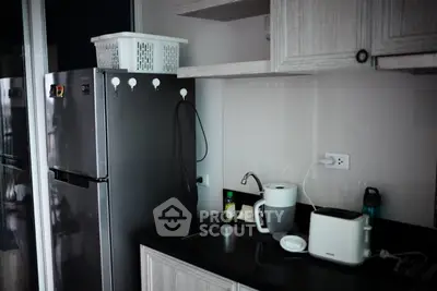 Modern kitchen with sleek appliances and compact design, featuring a stainless steel fridge and stylish cabinetry.