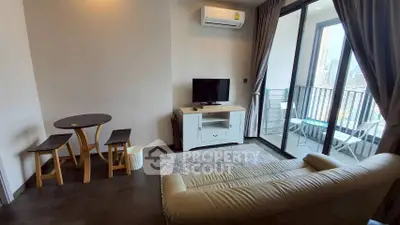 Modern living room with balcony view, featuring cozy seating and compact dining area.