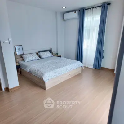 Spacious and bright bedroom with modern decor and large window, featuring a comfortable bed and stylish curtains.
