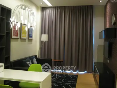 Modern living room with stylish decor, featuring a black leather sofa, green chairs, and unique lighting.