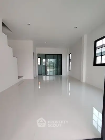 Spacious modern living room with sleek white flooring and large windows for natural light.