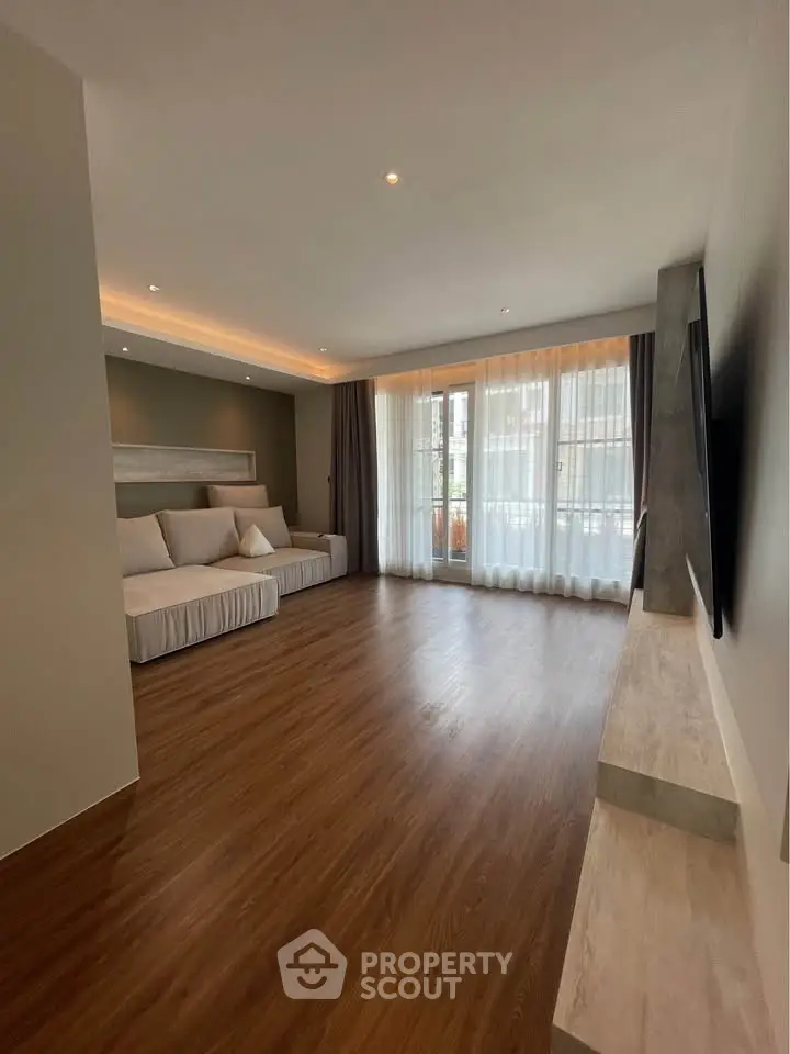 Spacious modern living room with large windows and elegant wooden flooring.
