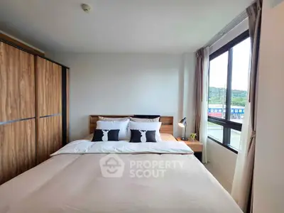 Spacious bedroom with large window and modern wooden wardrobe