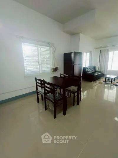 Spacious living room with dining area and modern furniture, featuring large windows for natural light.