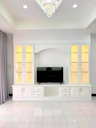 Elegant living room with built-in white entertainment center and modern chandelier.