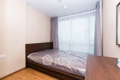 Cozy bedroom with wooden flooring and large window for natural light