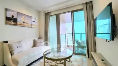 Modern living room with balcony view, stylish decor, and wall-mounted TV in a bright apartment.
