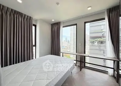 Spacious bedroom with large windows offering stunning city views in a modern high-rise apartment.