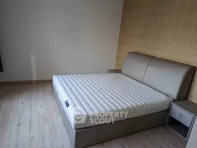 Spacious bedroom with modern bed and elegant wallpaper, perfect for a cozy retreat.