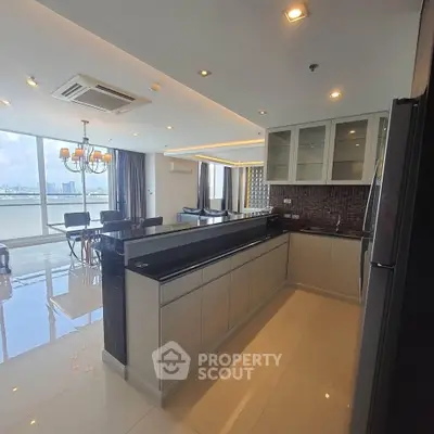 Luxurious open-layout kitchen with sleek cabinetry and stunning city view in modern apartment.