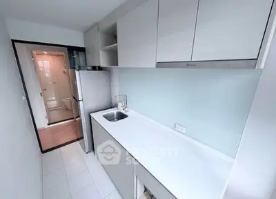 Modern kitchen with sleek cabinetry and stainless steel fridge in a compact layout.