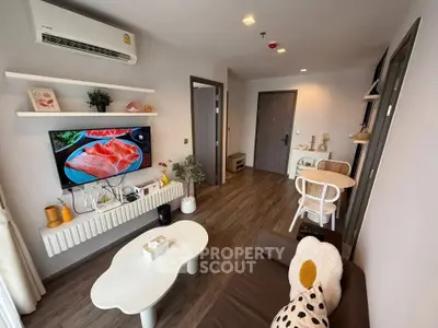 Modern living room with stylish decor and wall-mounted TV in cozy apartment.