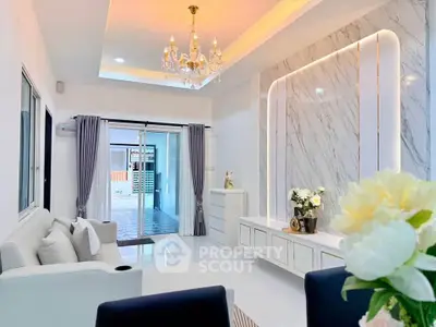 Elegant living room with chandelier and marble accent wall, featuring modern decor and natural light.