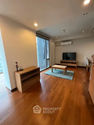 Spacious living room with wooden flooring and modern furniture in a stylish apartment.