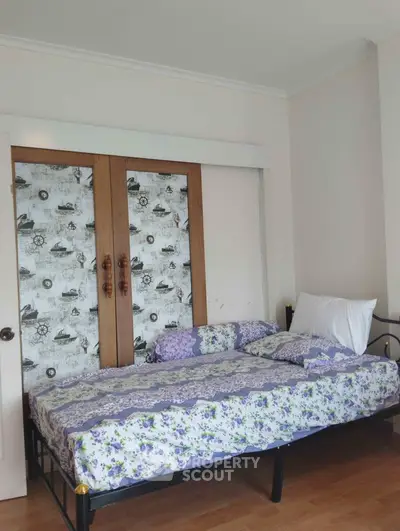 Cozy bedroom with large bed and unique nautical-themed wallpaper, wooden wardrobe doors, and ample natural light, perfect for restful living.