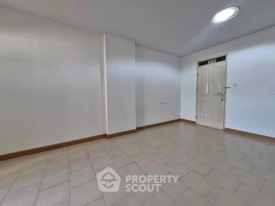 Spacious empty room with tiled flooring and white walls, ideal for customization.