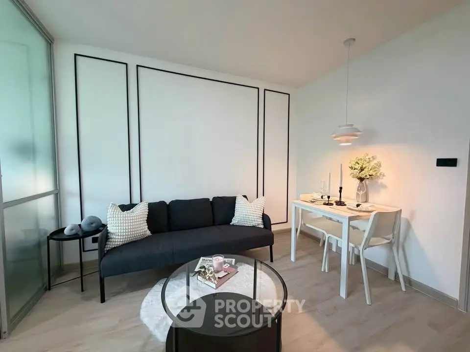 Modern living room with sleek black sofa, stylish dining area, and elegant decor in a bright, airy space.