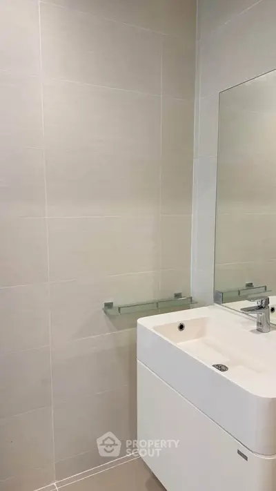 Modern bathroom with sleek sink and large mirror in a contemporary apartment.