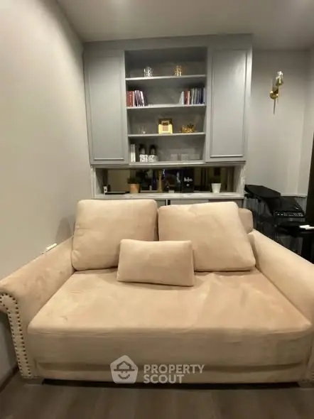 Cozy living room with plush beige sofa and built-in shelving unit.