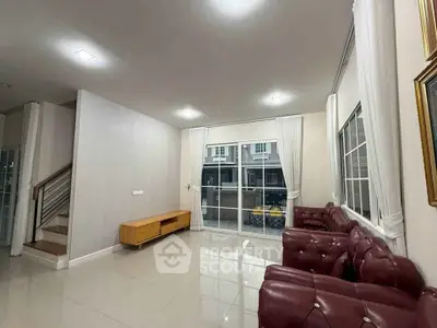 Spacious living room with elegant red leather sofas and large windows offering natural light.