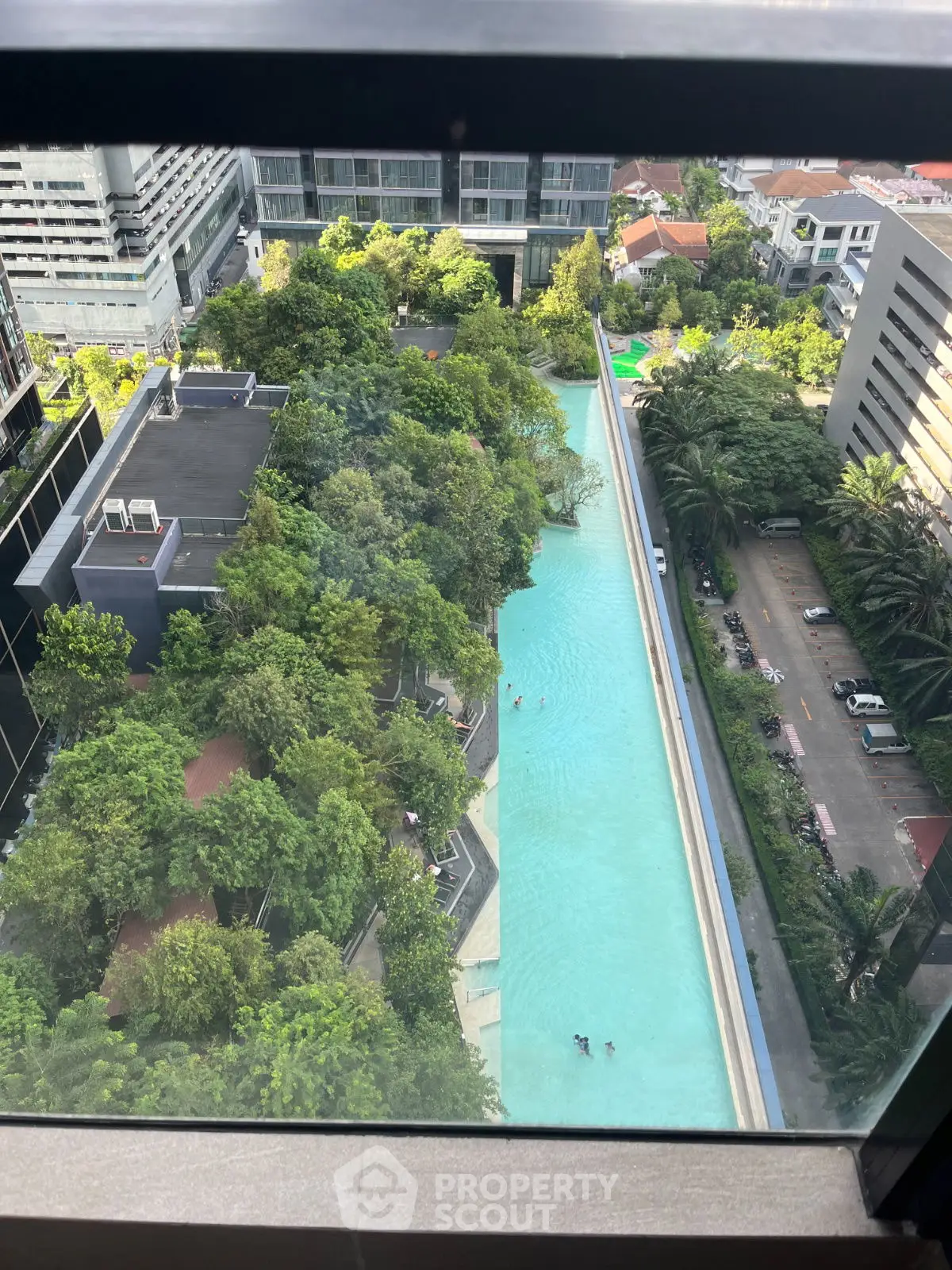 Stunning aerial view of a luxurious pool surrounded by lush greenery in a modern urban setting.
