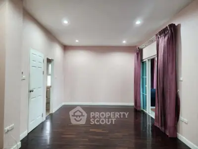 Spacious empty room with hardwood floors and large windows, perfect for customization.