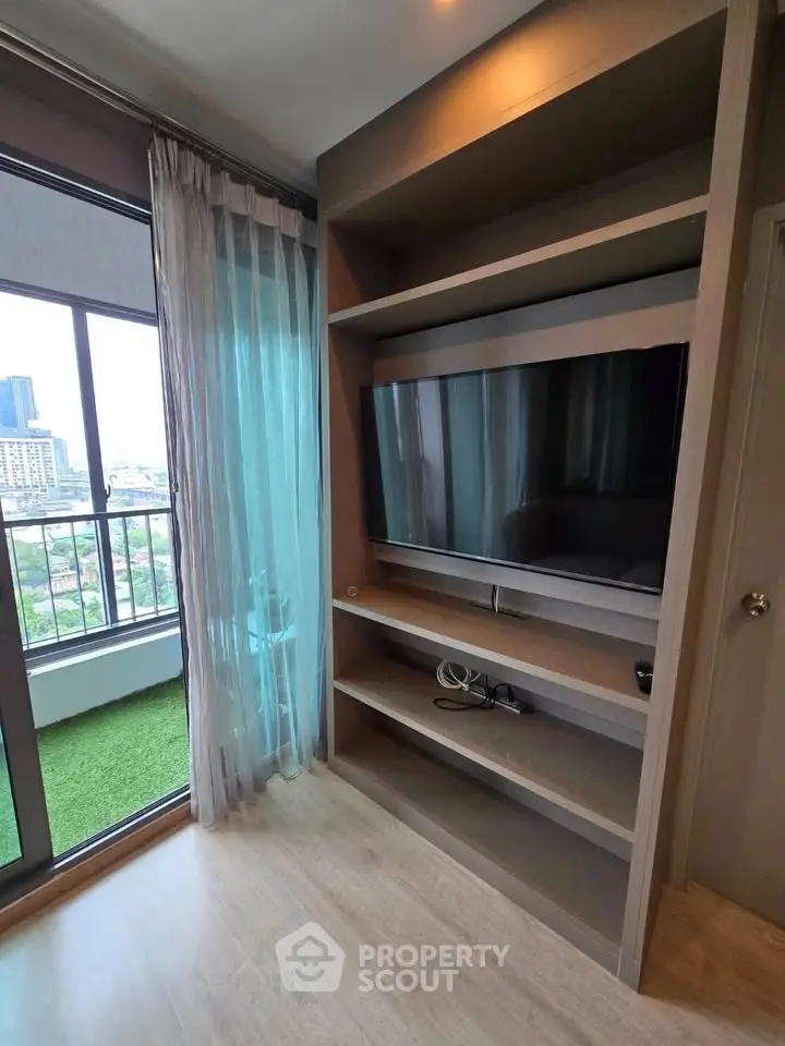 Modern living room with large TV and balcony view in urban apartment